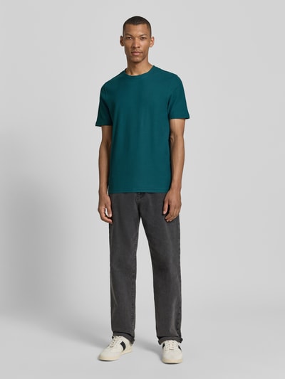 Męski model nosi T-Shirt mit Rundhalsausschnitt od MCNEAL w kolorze ciemnoturkusowym, krój slim fit, czysta bawełna, widok całej sylwetki z przodu. Długość tyłu w rozmiarze M: 68 cm.