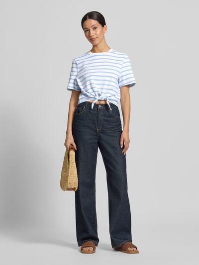 Frauenmodel trägt T-Shirt im Allover-Look mit Knotendetail von Rich & Royal aus Reine Bio-Baumwolle, Regular-Fit, Rundhalsausschnitt, Rückenlänge bei Größe S 48 cm, gestreiftes Muster in Weiß und Hellblau, ganzkörperansicht von vorne.