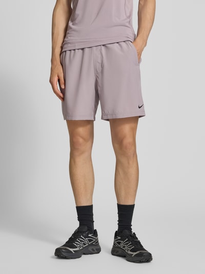 Mannenmodel draagt Shorts met Logo-Print en Eingrifftaschen van NIKE TRAINING in recht model, elastische band met trekkoord, zij-steekzakken, bandwijdte maat M 41 cm, binnenbeenlengte 19 cm, lichte effen kleur, gladde textuur, logoprint, volledige vooraanzicht