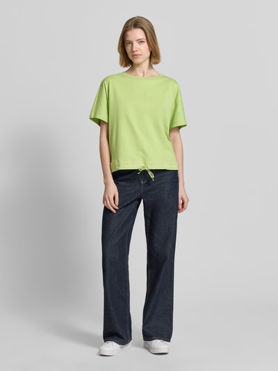 Frauenmodel trägt Oversized T-Shirt mit Rundhalsausschnitt von Smith and Soul aus reiner Baumwolle, Oversized-Fit, Saum mit Kordelzug, Rückenlänge bei Größe S 58 cm, kräftiges Grün, glatte Textur, Ganzkörperansicht von vorne.
