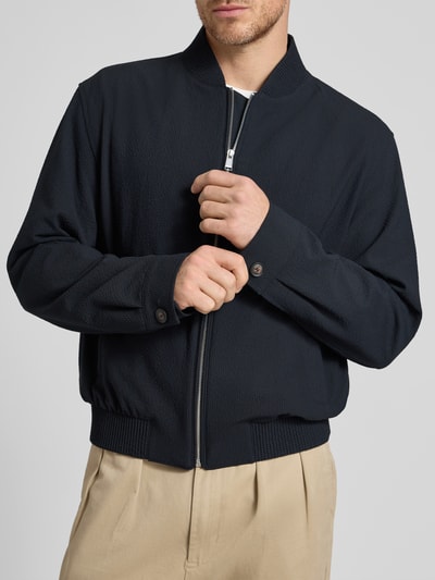 Männermodel trägt Regular Fit Blouson mit Baseball-Kragen Modell 'H-COMBO' von BOSS, Optik:Allover-Muster, Materialverarbeitung: Seersucker, gestreift, Reißverschluss, Langarm, Label-Applikation, gerippter Rumpfabschluss, seitliche Eingrifftaschen, Nahaufnahme Oberkörper.