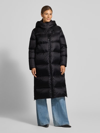 Vrouwenmodel draagt gewatteerde mantel met Capuchon, tweewegritssluiting, labeldetail, Model 'CELIA' van Blauer vs, regular fit, kleur zwart, Ganzkörperansicht von vorne. Ruglengte bij maat S: 110 cm, schouderbreedte: 43 cm, borstwijdte: 55 cm, mouwlengte: 60 cm.