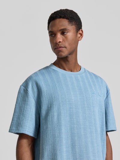 Männermodel trägt T-Shirt mit Strukturmuster und Rundhalsausschnitt von Les Deux in Hellblau, Material-Mix mit Viskose-Anteil, Regular-Fit, Rückenlänge bei Größe M 67 cm, Nahaufnahme Oberkörper.