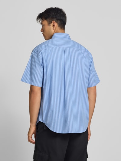 Männermodel trägt Regular Fit Freizeithemd mit Kentkragen Modell 'Keene' von Carhartt Work In Progress, blau-weiß gestreift, reine Baumwolle, Ganzkörperansicht Rückansicht.
