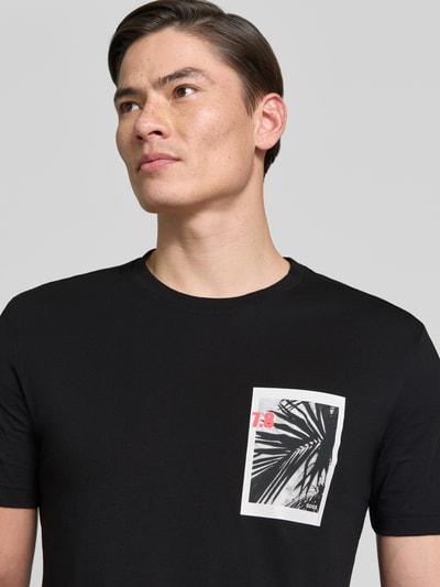 Männermodel trägt Regular Fit T-Shirt aus reiner Baumwolle Modell 'TE_BOARD' von BOSS Orange, unifarben, Foto-Print, Nahaufnahme Oberkörper.