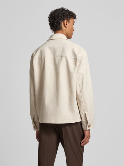 Mężczyznamodel nosi Regular Fit Hemdjacke aus Leinen-Baumwoll-Mix Modell 'LEWIS' od SELECTED HOMME, beżowy, gładki, długi rękaw, patkowe kieszenie, tekstura flammgarn, widok całej sylwetki od tyłu.