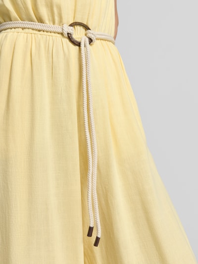 Frauenmodel trägt Jumpsuit aus Viskose-Mix mit Gürtel von Apricot in Hellgelb mit strukturierter Oberfläche, Detailaufnahme Taille. Taillierter Schnitt mit seitlichen Eingrifftaschen, Gürtel und Schlüsselloch-Ausschnitt, Viskose-Mix mit Leinen-Anteil.