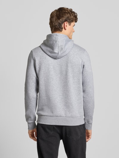 Męski model nosi Hoodie z label-printem i kieszenią kangurką od Jack & Jones, bawełna, regular fit, widok całej sylwetki z tyłu.