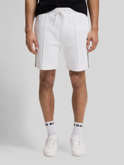 Männermodel trägt Regular Fit Sweatshorts aus Baumwoll-Mix Modell 'JT_JOIN HEADLO' von BOSS Green, Optik: Unifarben, Label-Applikation, Paspeln, Bundabschluss elastisch mit Tunnelzug, Reißverschlusstaschen, Materialverarbeitung: Sweat, Farbe Weiß, glatte Struktur, Ganzkörperansicht von vorne.