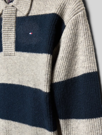 Mädchen trägt Relaxed Fit Strickpullover mit Woll-Anteil von Tommy Hilfiger Teens in Two-Tone-Optik, Logo-Stitching, Nahaufnahme Oberkörper.
