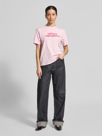 Frauenmodel trägt T-Shirt mit geripptem Rundhalsausschnitt Modell 'NORA' von Vila, locker geschnitten, rosa, Baumwoll-Elasthan-Mix, Ganzkörperansicht von vorne.