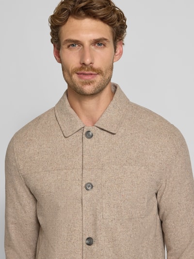 Męski model nosi Regular Fit Jacke mit Woll-Anteil von Lindbergh, elastyczna mieszanka materiałów, wykładany kołnierz, listwa guzikowa, kieszenie na piersi, długość tyłu w rozmiarze M: 72 cm, beżowa, tekstura melanż, zbliżenie na górną część ciała, widok z przodu.