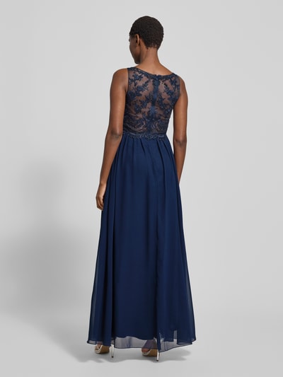Frauenmodel trägt Abendkleid mit Ziersteinen und floralen Stickereien von LAONA in Dunkelblau, taillierte Passform, doppellagiger Rockteil, Ganzkörperansicht Rückansicht. Rückenlänge 145 cm, Brustweite 40 cm bei Größe 36.