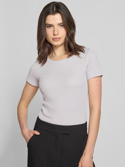 Vrouwenmodel draagt T-shirt met Label-Detail van Marc Cain in lichtgrijs, elastische materiaalmix, nauwsluitend model, u-hals, labeldetail, ruglengte bij maat 36: 55 cm, vooraanzicht van het bovenlichaam