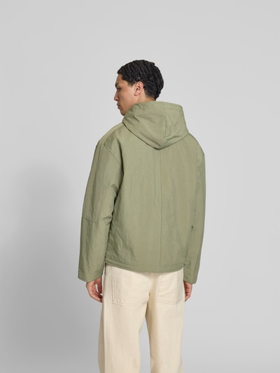 Männermodel trägt Regular Fit Jacke mit Kapuze von WON HUNDRED in Hellgrün, Känguru-Tasche, Reißverschluss, Tunnelzug, Rückansicht, Ganzkörperansicht. Rückenlänge 69 cm, Schulterbreite 56 cm, Ärmellänge 63 cm, Größe M.