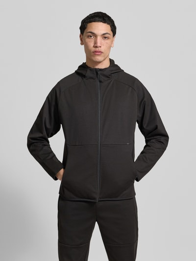 Männermodel trägt Regular Fit Sweatjacke mit Kapuze Modell 'Base' von Jack & Jones in Schwarz, sichtbare Reißverschlusstaschen, Ganzkörperansicht von vorne, elastischer Material-Mix mit Baumwoll-Anteil.