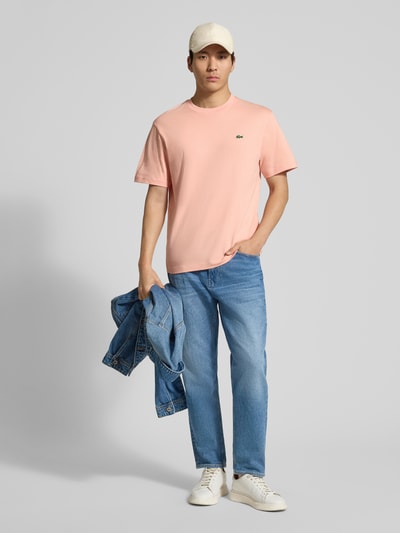 Männermodel trägt Regular Fit Poloshirt aus reiner Baumwolle von Lacoste in Optik: Unifarben mit Logo-Stitching, Rundhals, Kurzarm, Ganzkörperansicht von vorne.
