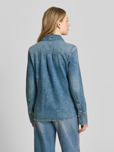 Frauenmodel trägt Hemdbluse in Denim-Optik mit Rüschenbesatz Modell 'Dulce' von Mango, reine Baumwolle, Ganzkörperansicht Rückansicht.