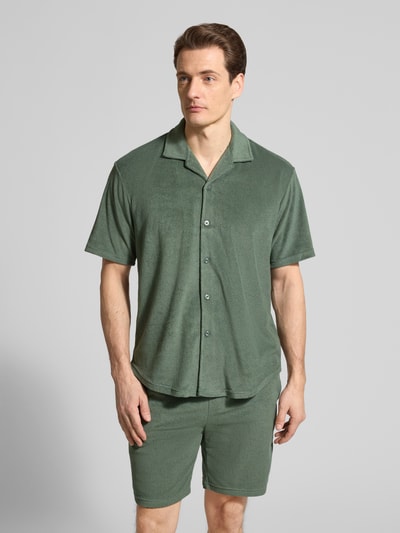 Męski model nosi Slim Fit Freizeithemd aus Frottee od MCNEAL, bawełniana mieszanka, krój slim fit, koszula z krótkim rękawem, przód w całości na guziki, kolor zielony, tekstura frotte, z kołnierzem rewersowym, długość pleców 71 cm, szerokość w rozmiarze M 53 cm, długość rękawa 24 cm, widok całej sylwetki z przodu