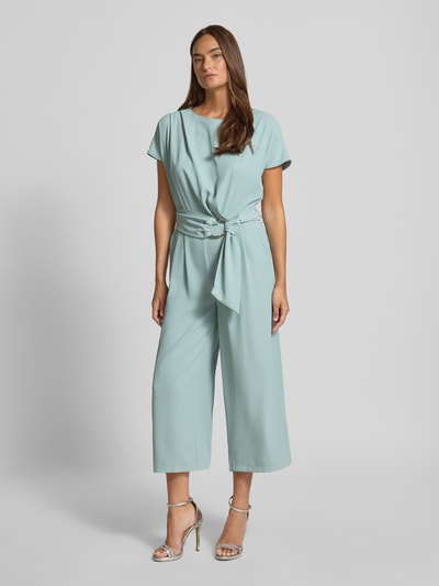 Frauenmodel trägt Jumpsuit mit Stretch-Anteil von Betty Barclay in Hellblau, elastischer Stoff, Gürtel, 7/8-Länge, Ganzkörperansicht von vorne.