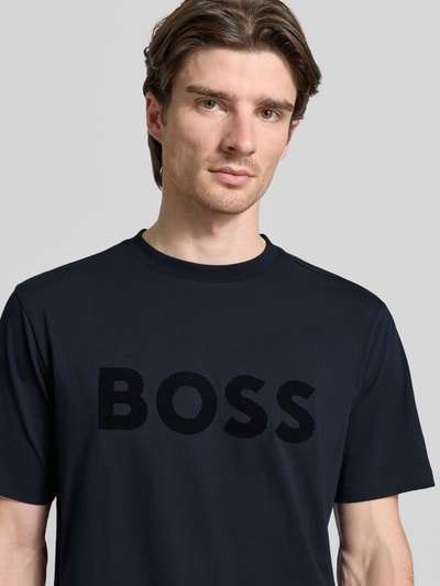 Männermodel trägt Regular Fit T-Shirt aus Baumwoll-Mix Modell 'ICONIC' von BOSS Green in Dunkelblau, unifarben, Nahaufnahme Oberkörper.