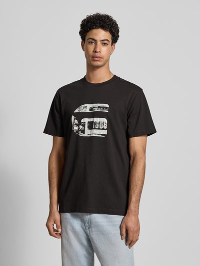 Männermodel trägt Regular Fit T-Shirt mit Logo-Print Modell 'icon' von G-Star Raw in Schwarz aus reiner Baumwolle, Rundhalsausschnitt, Ganzkörperansicht von vorne.