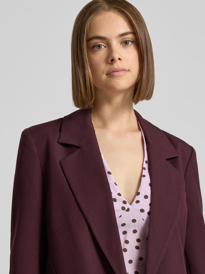 Kobieta nosi Regular Fit Longblazer mit 1-Knopf-Verschluss von ONLY w kolorze bordowym, gładka tekstura, zbliżenie na górną część ciała, damski longblazer od ONLY.
