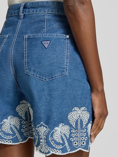 Frauenmodel trägt Shorts mit Lochstickerei Modell 'PILAR' von Guess aus reiner Baumwolle, Wide-Fit, Gesäßtasche, Detailaufnahme Rückansicht.