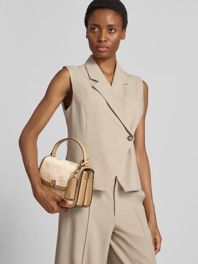 Vrouwenmodel draagt schoudertas met overslag van GUESS in beige met all-over merkprint, Labelhanger, magneetsluiting, detailopname.