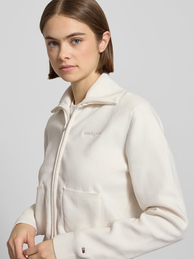 Frauenmodel trägt Slim Fit Strickjacke mit aufgesetzten Taschen von Tommy Jeans in Optik: Unifarben, Strickoptik, Nahaufnahme Oberkörper.