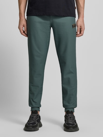 Männermodel trägt Regular Fit Sweatpants mit Strukturmuster von EA7 Emporio Armani, Elastischer-Material-Mix, Eingrifftaschen, Nahaufnahme Unterkörper.