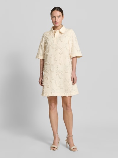 Frauenmodel trägt Minikleid mit kurzer Knopfleiste Modell 'Mialle' von mbyM, Strukturmuster, Gerader-Schnitt, Polokragen, cremefarben, Ganzkörperansicht von vorne. Rückenlänge bei Größe S: 89 cm, Brustweite: 34 cm, Ärmellänge: 36 cm.