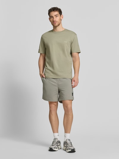 Männermodel trägt Relaxed Fit T-Shirt mit Rückenprint von HUGO, Farbe Mehrfarbig, Optik: mehrfarbig, Passform: Relaxed-Fit, Label-Print, Rundhals, Ärmelform: Kurzarm, Material: Reine Baumwolle, Ganzkörperansicht von vorne.