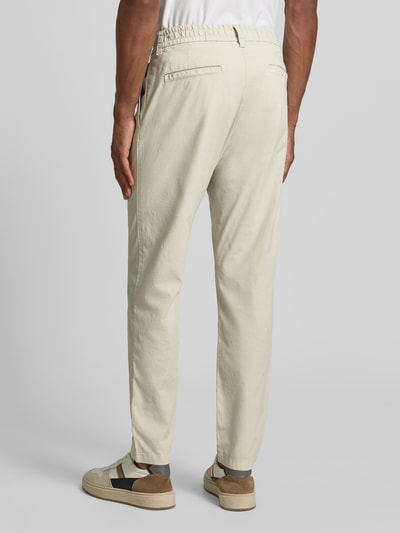 Männermodel trägt jednokolorowe chinosy z mieszanki bawełny BOSS Orange Tapered Chino aus Baumwoll-Mix Modell 'CHINO-TAPERED-DS-10', efekt: jednolity kolor, krój tapered fit, szlufki na pasek, tunel, elastyczny ściągacz, zapięcie na guzik i zamek błyskawiczny, kieszenie wpuszczane boczne, kieszenie z tyłu, mieszanka bawełny, Ganzkörperansicht Rückansicht.