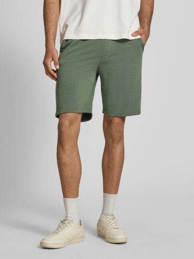 Männermodel trägt grüne Sweatshorts mit elastischem Bund Modell 'KARLOS' von Blend, Baumwoll-Mix, Regular-Fit, Nahaufnahme Oberkörper bis Knie, Bundweite bei Größe M 42 cm, Innenbeinlänge 21 cm.