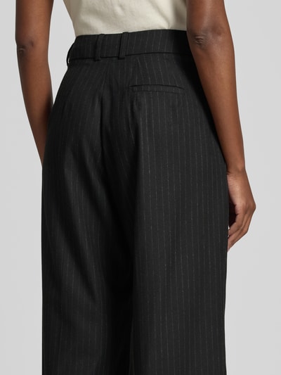 Frauenmodel trägt Wide Fit Hose mit Viskose-Anteil von black palms mit Bundfalten, Gesäßtasche im Elastischer-Material-Mix, Detailaufnahme Rückansicht.