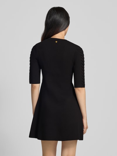 Frauenmodel trägt Minikleid aus Viskose-Mix Modell 'Abito Maglia' von Liu Jo White in Schwarz mit Zierbesatz, Ganzkörperansicht Rückansicht.
