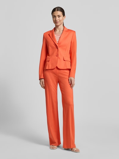 Frauenmodel trägt Slim Fit Blazer aus Viskose-Mix von Marc Cain in kräftigem Orange mit Reverskragen, Pattentaschen, 2-Knopfleiste, Ganzkörperansicht von vorne. Rückenlänge bei Größe 36: 55 cm, Brustweite: 41 cm, Ärmellänge: 62 cm.