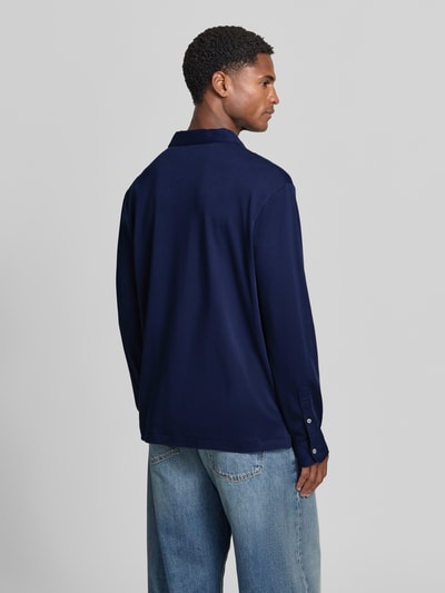 Männermodel trägt dunkelblaues Slim Fit Poloshirt aus reiner Baumwolle von Polo Ralph Lauren zu hellblauen Jeans, Ganzkörperansicht Rückansicht.