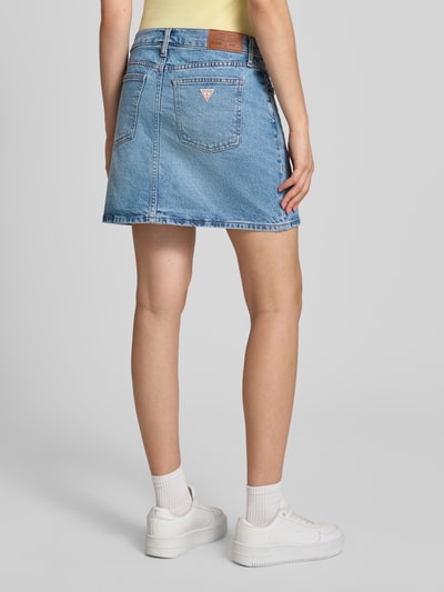 Frauenmodel trägt Jeansrock mit Eingrifftaschen von GUESS, Baumwoll-Elasthan-Mix, blauer Minirock mit geradem Schnitt, Ganzkörperansicht Rückansicht.
