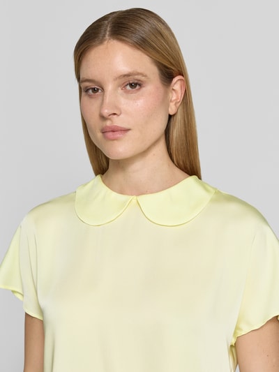 Modelka kobieca ma na sobie Blusenshirt aus Satin mit Umlegekragen od Marc Cain, jasnożółty, satynowa tekstura, krój regular fit, zapięcie na guzik z tyłu, długość tyłu 59 cm, długość rękawa 20 cm, zbliżenie na górę ciała.