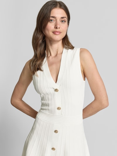 Frauenmodel trägt Knielanges Kleid aus Viskose-Mix Modell 'Amber' von Guess in Weiß mit Strick-Optik, taillierte Passform, V-Ausschnitt, ärmelloses-Design; Nahaufnahme Oberkörper.