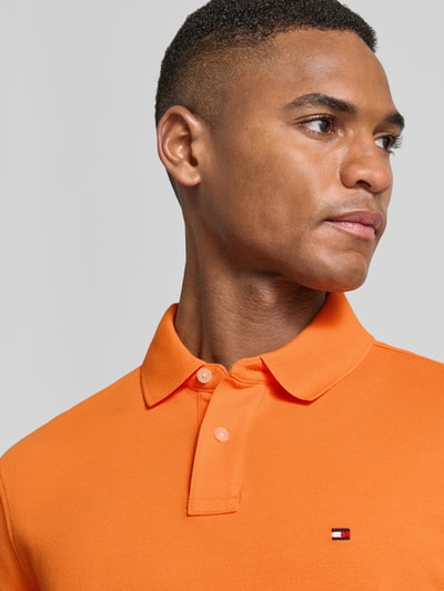 Männermodel trägt Regular Fit Poloshirt aus Baumwoll-Mix von Tommy Hilfiger, Optik: Unifarben, Logo-Stitching, Nahaufnahme Oberkörper.