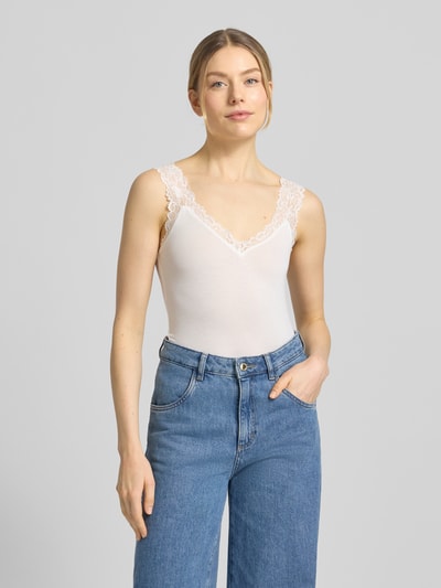 Frauenmodel trägt Slim Fit Tank Top aus Viskose-Mix Modell 'ROSA' von Vero Moda, Optik: Unifarben, Rüschen-Applikation, V-Ausschnitt, breite Träger, Materialverarbeitung: Feinripp, Nahaufnahme Oberkörper.
