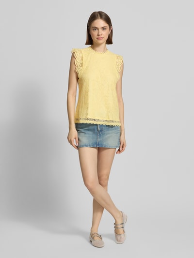 Frauenmodel trägt Shaped Fit Blusentop mit Spitzenbesatz Modell 'OLLINE' von Pieces, Optik: Unifarben, Muster: Floral, Label-Stitching, Rundhals, 1-Knopf-Verschluss, Rückenausschnitt: Schlüsselloch, Materialverarbeitung: Spitze in zartem Gelb, Ganzkörperansicht von vorne.