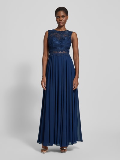 Frauenmodel trägt Abendkleid mit floralen Stickereien von Mascara, taillierte Passform, ärmellos, mehrlagiger Rockteil, Reißverschluss, Ganzkörperansicht von vorne.
