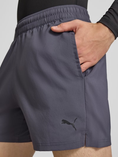 Männermodel trägt Regular Fit Sportshorts mit Logo-Print Modell 'TAD ESSENTIALS' von PUMA in Dunkelgrau, Nahaufnahme Oberschenkel, Herren Sportshorts von PUMA Performance