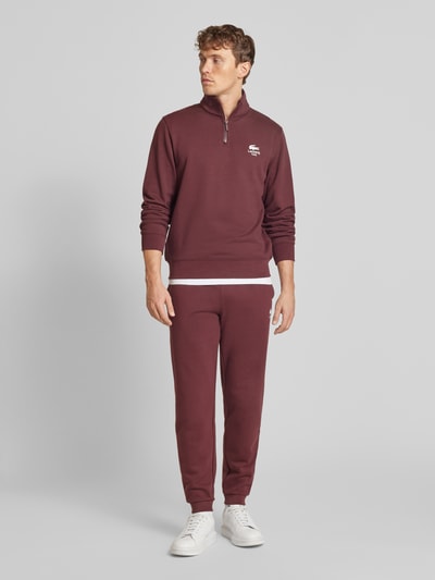 Lacoste Spodnie dresowe o kroju tapered fit z nadrukiem z logo model ‘HERITAGE’ Bordowy 1