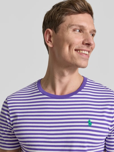 Männermodel trägt Slim Fit T-Shirt aus reiner Baumwolle von Polo Ralph Lauren, lila-weiß gestreift mit grünem Logo, Nahaufnahme Oberkörper.
