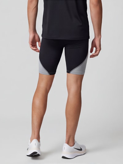 Männermodel trägt Slim Fit Sportshorts mit Logo-Print von Under Armour in Schwarz und Grau, glatte Textur, Ganzkörperansicht Rückansicht. Herren Sportshorts von Under Armour
